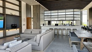 A modern lounge area with a large seating area, a bar, and a kitchen visible through a large window. - Mi Zona Lodging Reforma (Mexico City)
