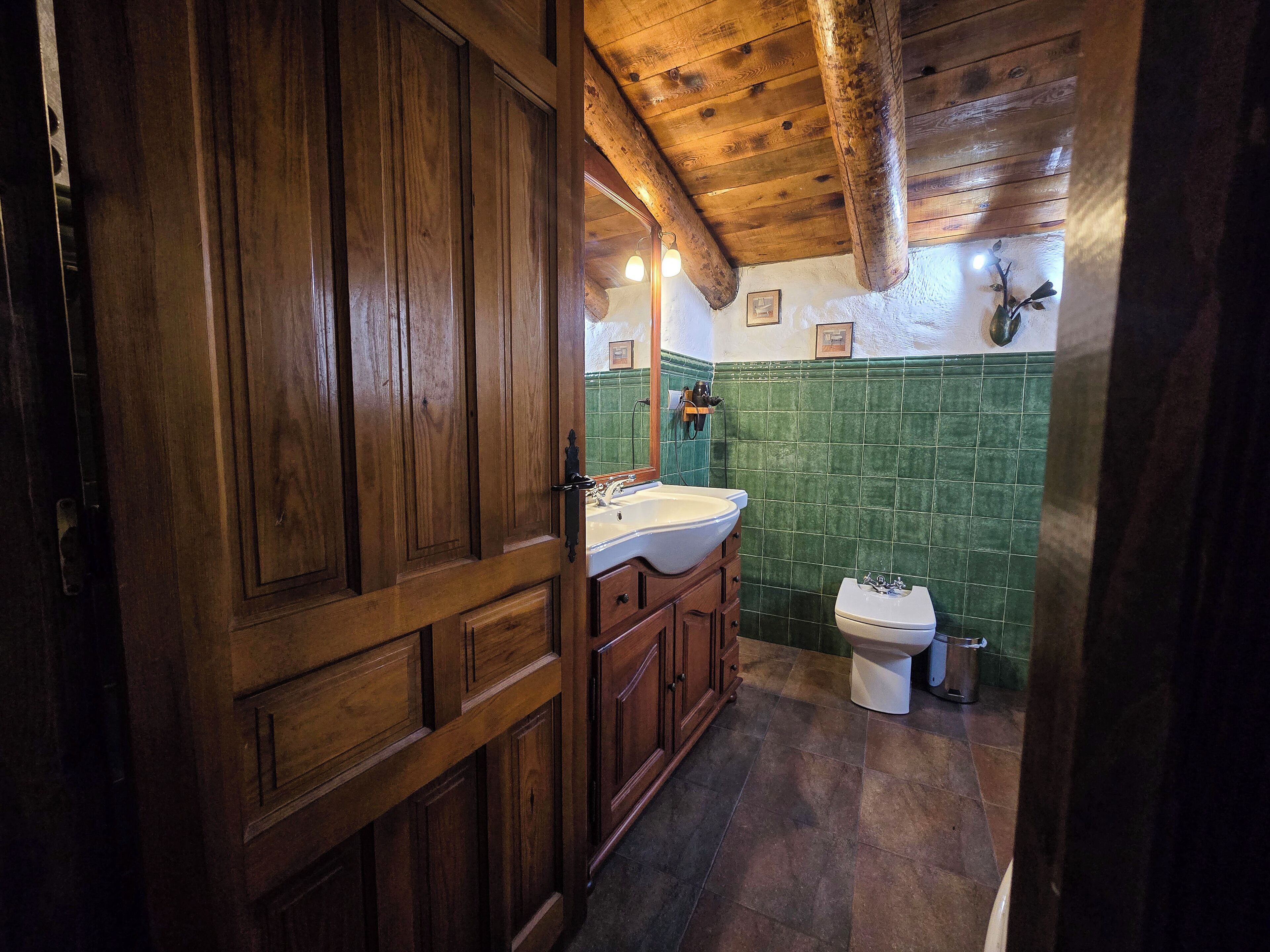 Bany amb panells de fusta, un rentapeus, un lavabo i un vàter.