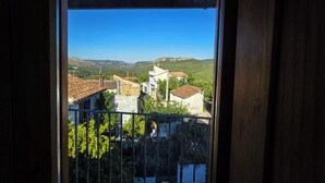 Ένα μπαλκόνι με θέα σε ένα χωριό, συμπεριλαμβανομένων κτιρίων και λόφων.
