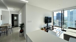Een modern appartement met een eetgedeelte, een woonruimte met een groot raam en uitzicht op de stad.