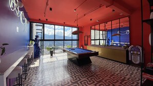 Een moderne kamer met een pooltafel, een bar en grote ramen met uitzicht op de stad.