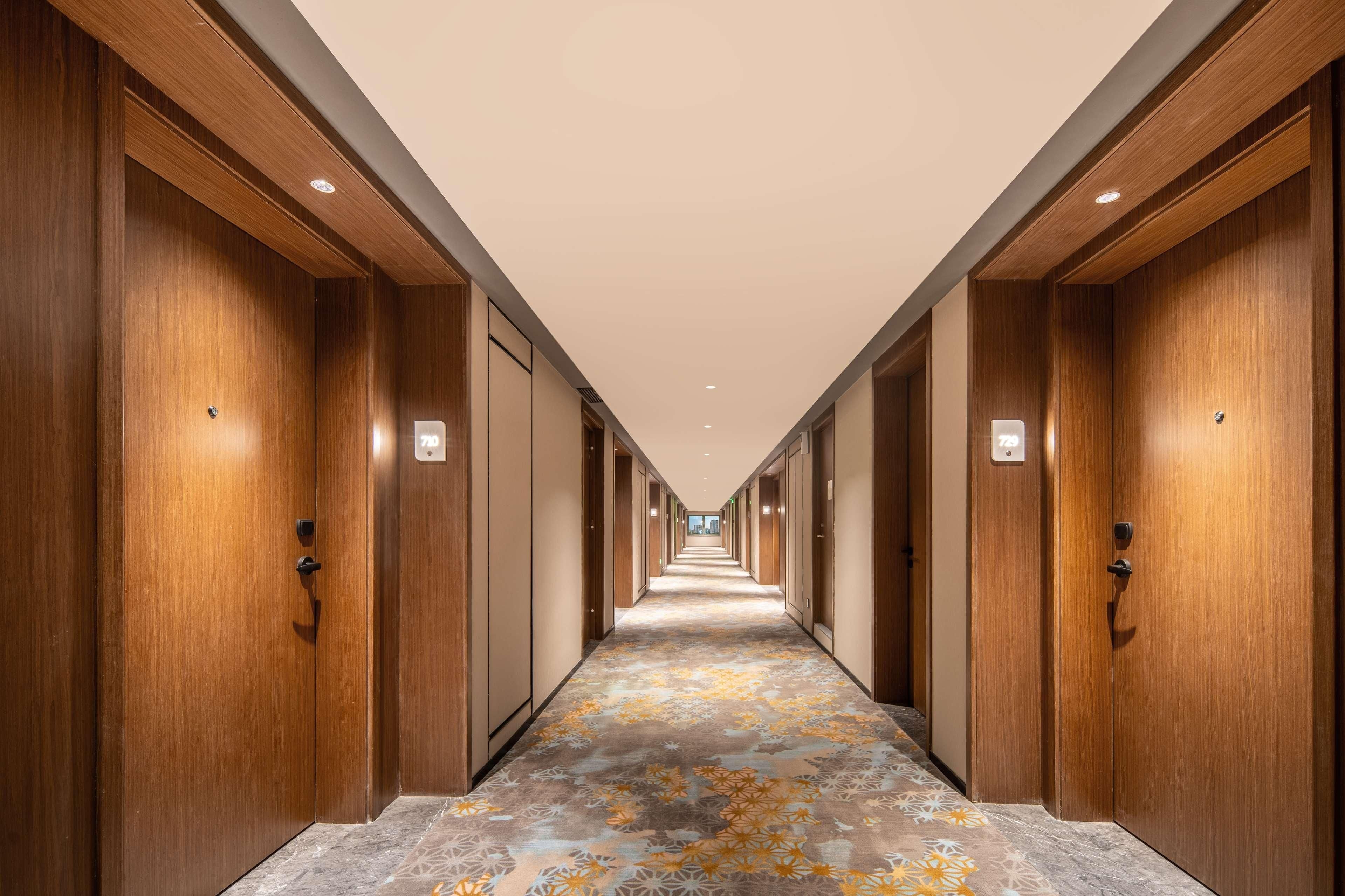 A long hallway with wooden doors and a patterned carpet.