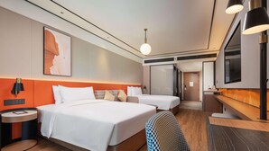 Habitació d'hotel amb dos llits, un escriptori, una cadira, un televisor i una obra d'art gran a la paret.