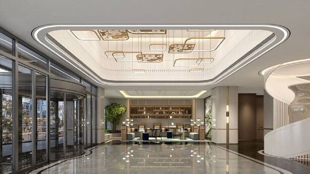 Un vestíbulo espacioso con un mostrador de recepción curvo, una planta grande y un techo alto con iluminación decorativa.