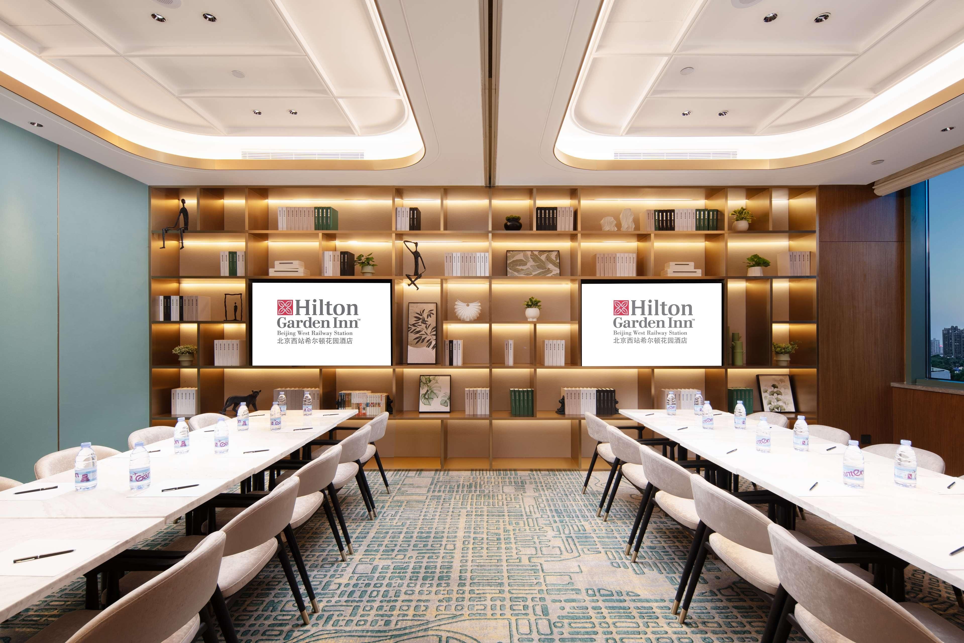 A conference room with a long table, chairs, water bottles, and a carpeted floor.