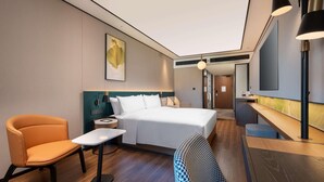 Una habitació d'hotel moderna amb un llit, una taula de treball, una cadira i una taula petita.