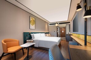 Ein modernes Hotelzimmer mit einem Bett, einem Schreibtisch, einem Sessel und einem kleinen Tisch.