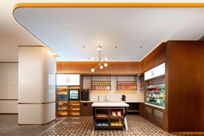 A modern hotel lobby with a central counter, vending machines, and a refrigerated display. - Hilton Garden Inn Beijing West Railway Station (Beijing)