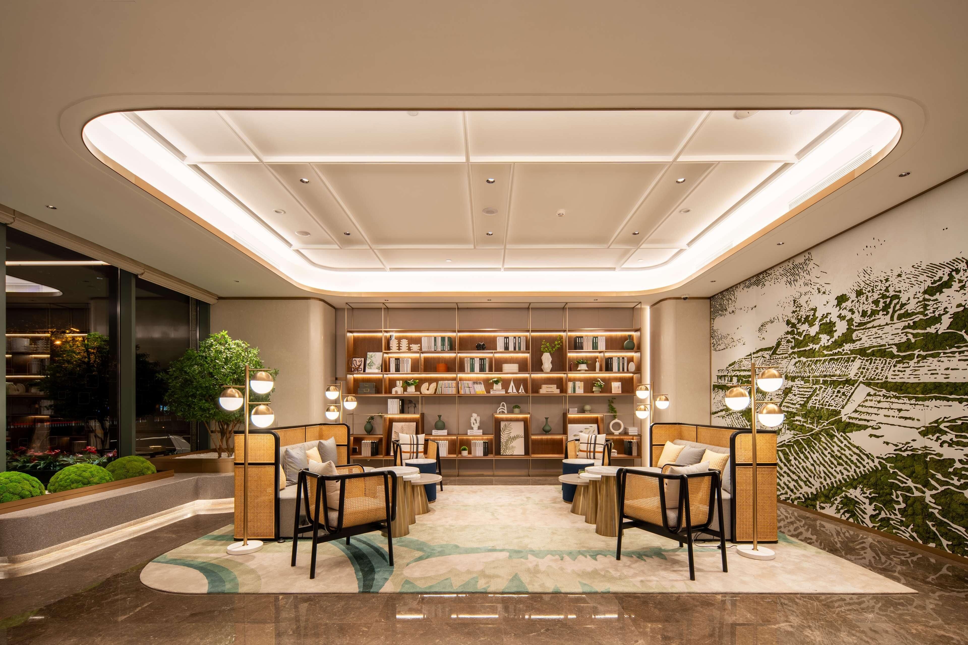 A modern lobby with a central seating area, bookshelves, and a decorative wall mural.
