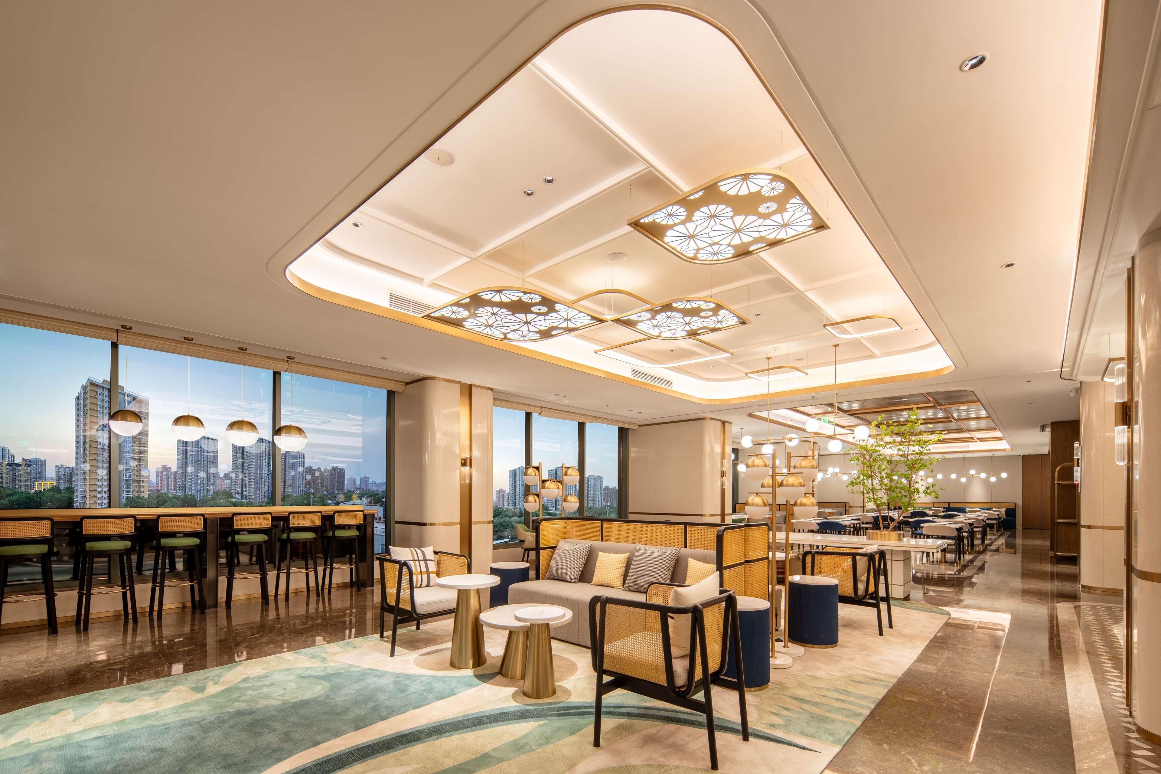 Um hall de hotel moderno com vista para a cidade, áreas de estar e um bar.