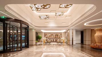 Un vestíbulo moderno con una zona de estar central, entrada de vidrio y un techo decorativo.
