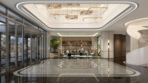 Un vestíbul ampli amb una taulell de recepció corbada, una planta gran i un sostre alt amb il·luminació decorativa.