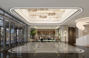 Eine großzügige Lobby mit einer gebogenen Rezeption, einer großen Pflanze und einer hohen Decke mit dekorativer Beleuchtung.