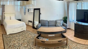 Un espacio habitable compacto con kitchenette, cama, sofá y televisor.