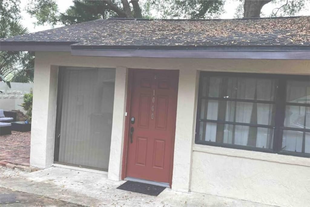 A small building with a red door, large windows, and a tiled roof.