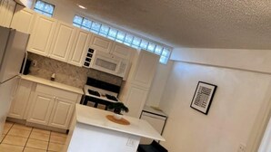 A compact kitchen with white cabinets, a central island, and a microwave.