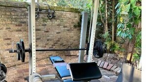 An outdoor gym with a bench press, dumbbells, and a weight rack.