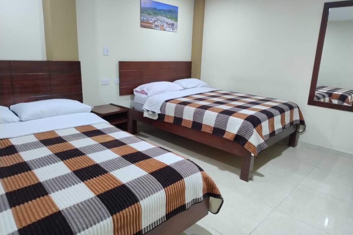 A hotel room with two single beds, a nightstand, a mirror, and a painting on the wall.