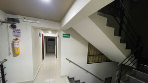 A hallway with a fire extinguisher, a sign for the staircase, and a tiled floor. - Rialto Suite (San Juan de Pasto)