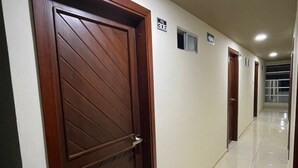 A hallway with wooden doors, a tiled floor, and a ceiling light. - Rialto Suite (San Juan de Pasto)
