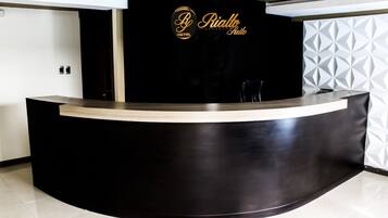 A reception desk with a black counter and a logo that reads "Rialto Hotel Suite".