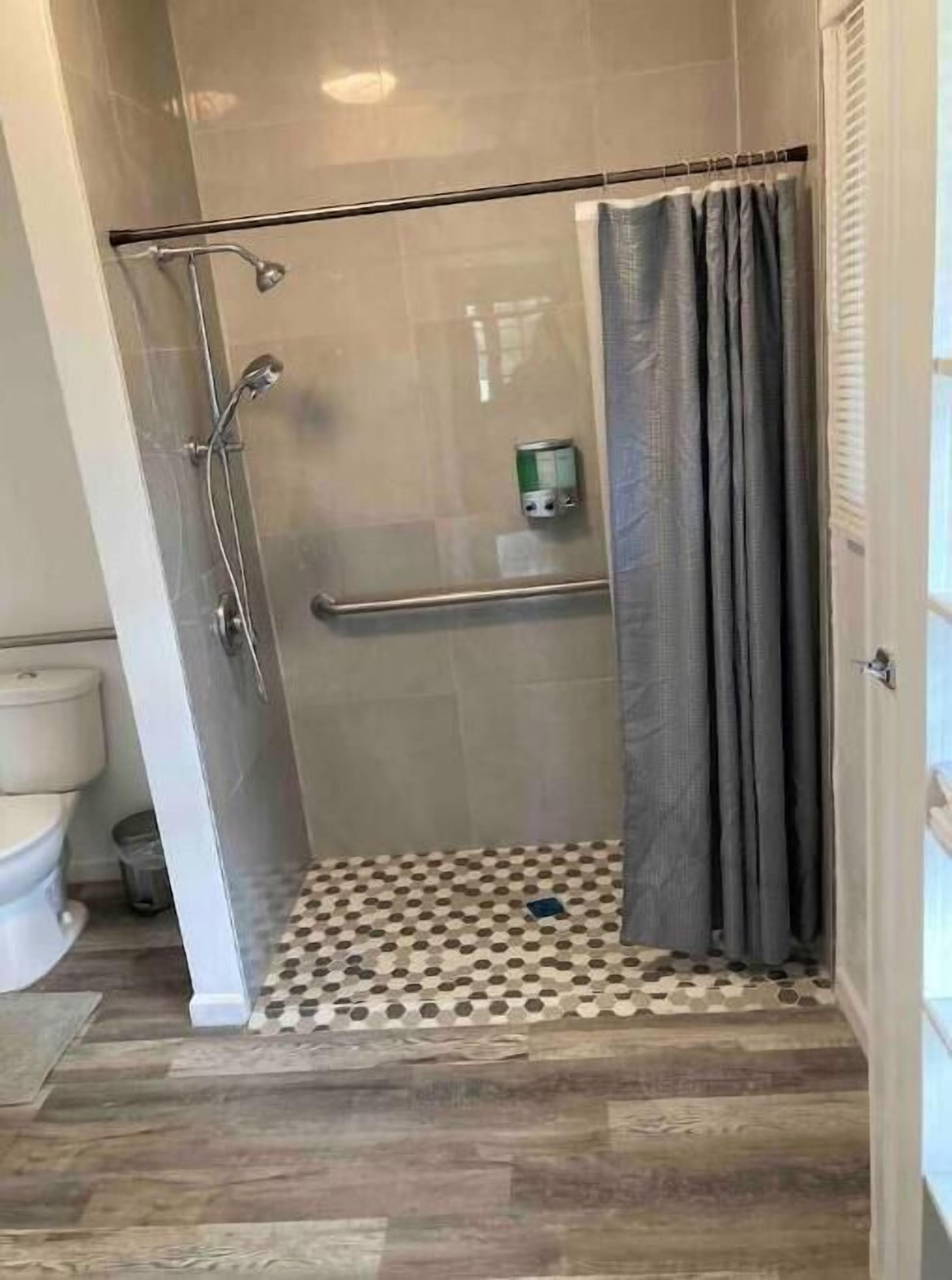 Une douche avec une porte en verre, un porte-serviettes et des toilettes.