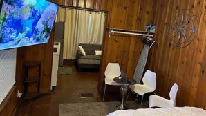 A room with wooden paneling, a television, a bed, a desk, a chair, and a guitar hanging on the wall. - Peaceful Private Gated Patio Walk to Mall Publix

 (Altamonte Springs)