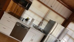 A kitchen with white cabinets, stainless steel appliances, and a wooden ceiling. - Peaceful Private Gated Patio Walk to Mall Publix

 (Altamonte Springs)