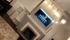 A living room with a flat-screen TV mounted on the wall, a fireplace, and a chandelier.