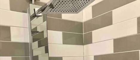 Eine Dusche mit Glastür, einer Handbrause und einem Handtuchhalter.