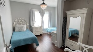 Ein Schlafzimmer mit Bett, Kommode, Stuhl und Spiegel.