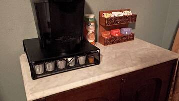 A coffee maker on a countertop with a Star Wars poster on the wall.