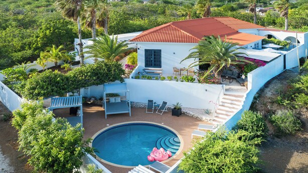 Una casa con piscina, mobiliario exterior y vistas a la vegetación circundante.