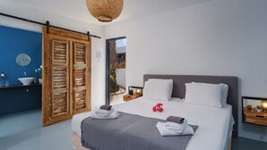 Un dormitorio con una cama grande, un baño con pared azul y una puerta de madera.