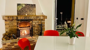A dining area with a stone fireplace, red chairs, and a white table. - Ca de Matette located just a few minutes' drive from beautiful Finalborgo. (Liguria)