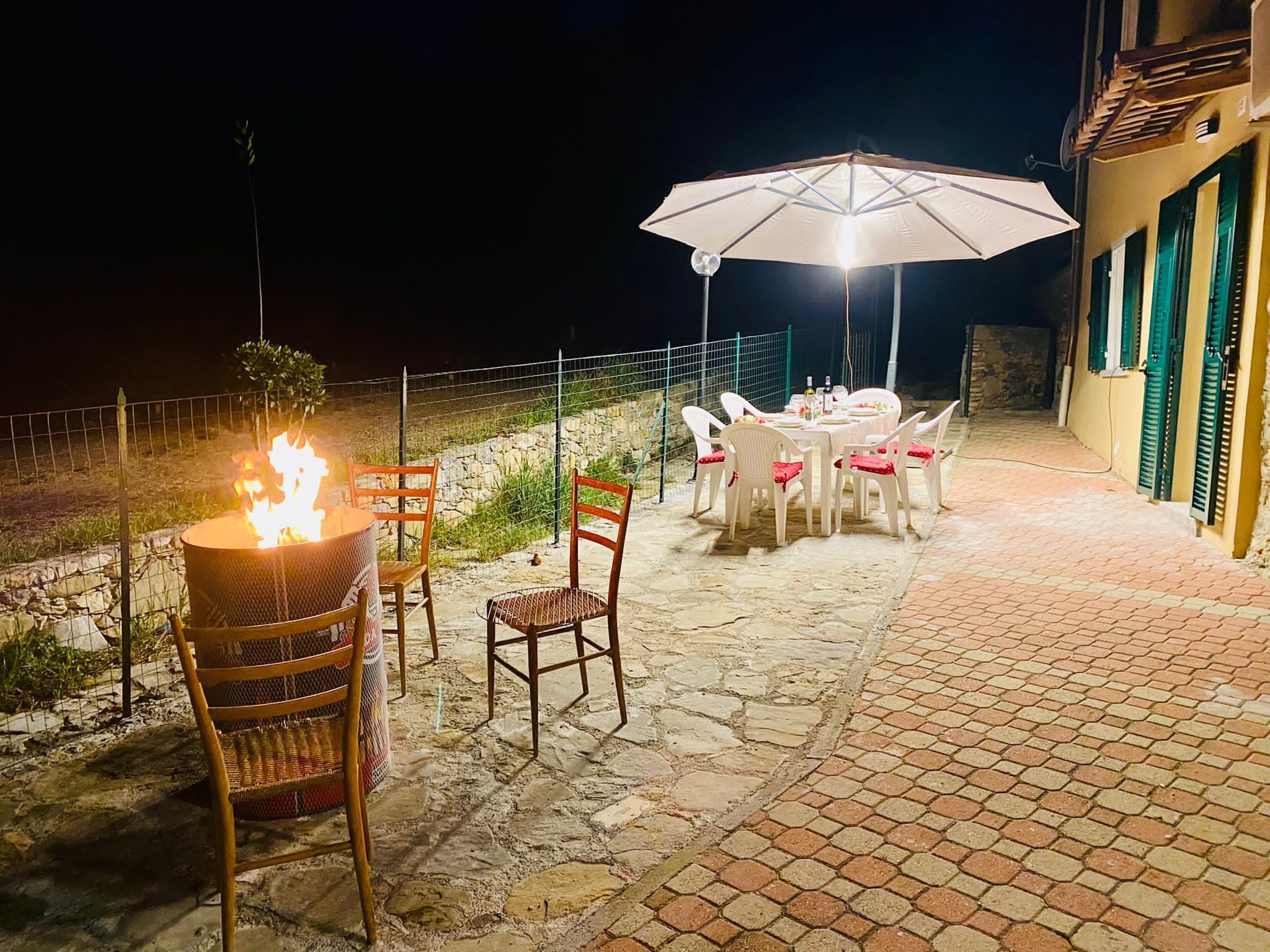 Une terrasse extérieure avec une table et des chaises, un foyer et un parasol.