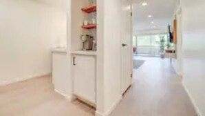 A hallway with a white door, a small cabinet, and a shelf with red items. - Walk to Old Town. Heated Pool. Hot tub. Gym. (Scottsdale)