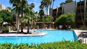 A swimming pool surrounded by palm trees and a building with balconies. - Walk to Old Town. Heated Pool. Hot tub. Gym. (Scottsdale)