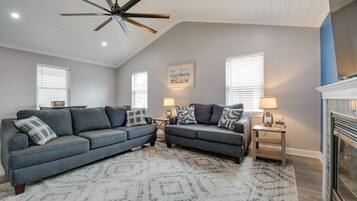 A living room with a sectional sofa, two side tables with lamps, a ceiling fan, and a fireplace.