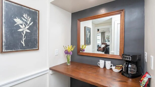 Un espace d’accueil d’hôtel avec un comptoir en bois, une machine à café et un vase rempli de fleurs.