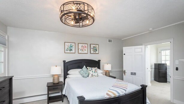 A bedroom with a bed, bedside tables, a chandelier, and framed artwork on the wall.