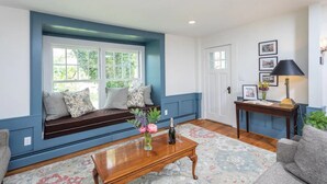 A living room with a built-in bench, a wooden coffee table, a lamp, and a door with framed pictures.