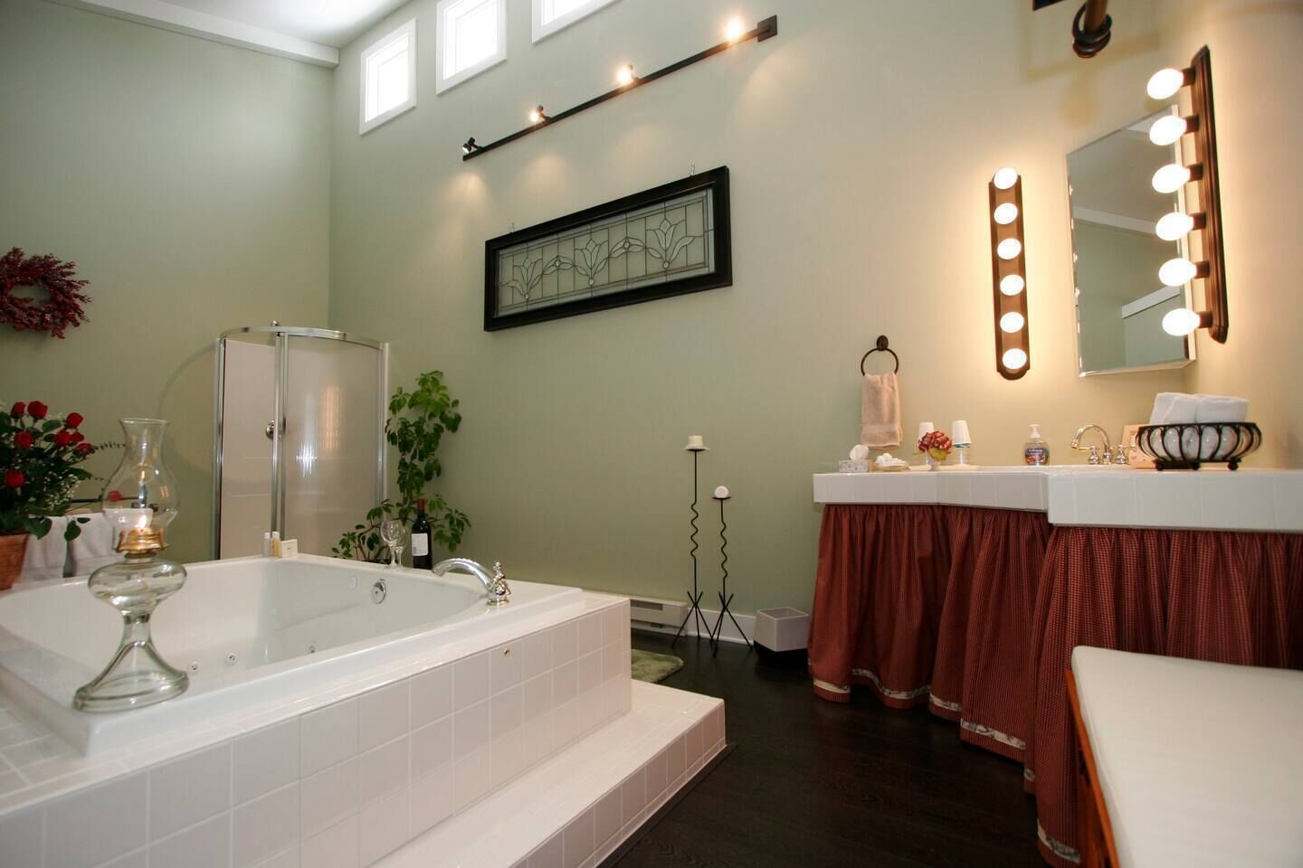 A bathroom with a large bathtub, a vanity with a mirror, and a shower.
