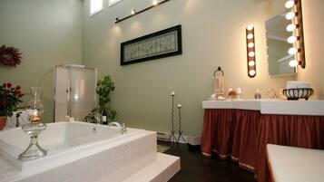 A bathroom with a large bathtub, a vanity with a mirror, and a shower.