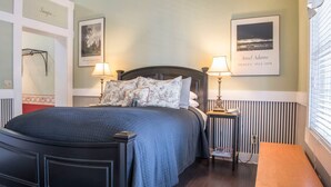 Une chambre à coucher bien rangée, avec un grand lit, deux tables de chevet et une petite table de nuit.