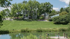 A residential area with a pond, a wooden dock, and houses with a well-maintained lawn.