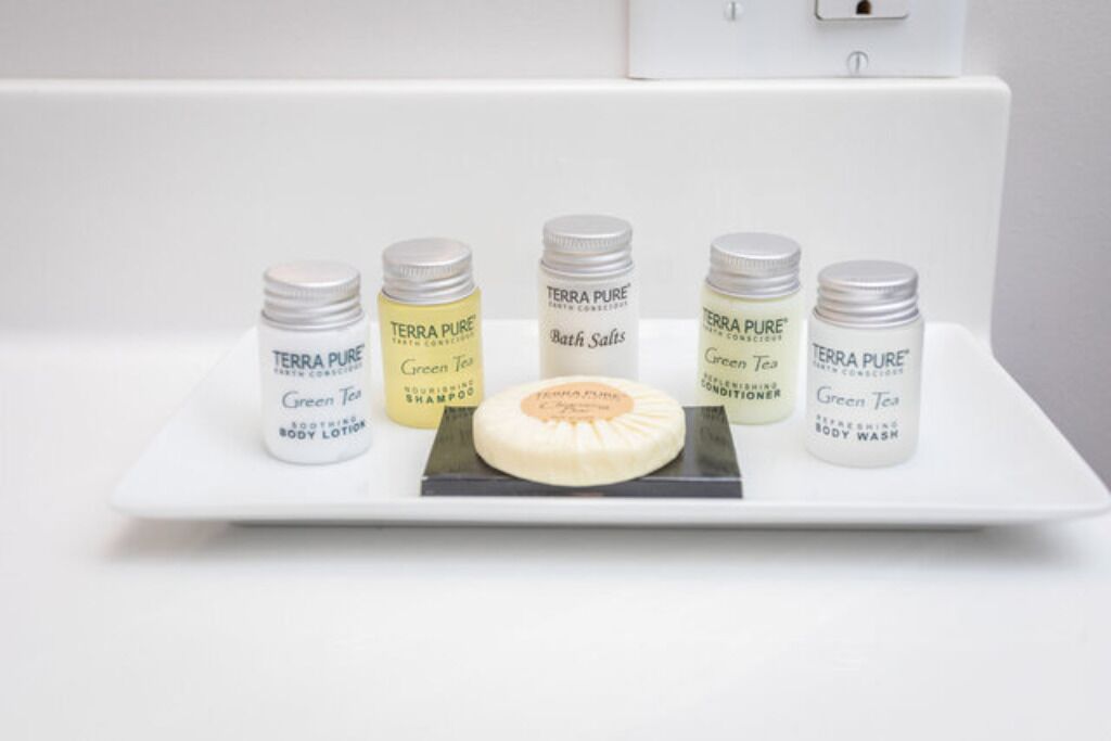A white shelf with five Terra Pure products: Green Tea Body Lotion, Nourishing Shampoo, Bath Salts, Refreshing Body Wash, and Green Tea Body Conditioner.