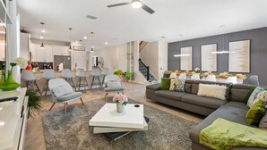 Un salon moderne avec un canapé, une table basse et des fauteuils. Un escalier mène à un autre niveau.