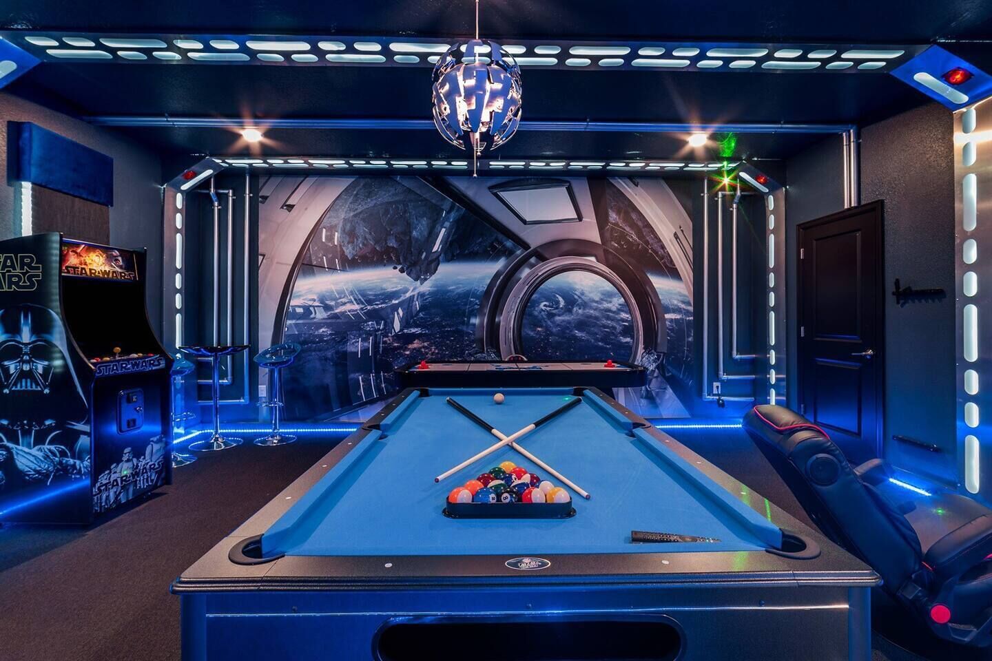 Ein Billardtisch in einem Raum mit Star Wars-Dekor, darunter ein großes Wandgemälde und eine Star Wars-Spielhalle.