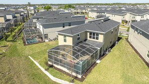 Un quartier résidentiel avec des maisons modernes, une grande structure entièrement vitrée et une piscine.